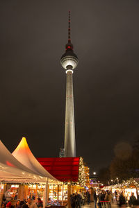 Communications tower in city against sky at night