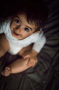 High angle portrait of of cute baby sitting on bed