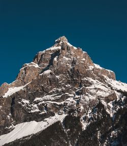 Low angle view of rock formation against clear blue sky