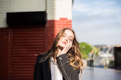 Portrait of young woman standing against wall