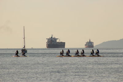 People on sea against clear sky