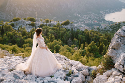 Rear view of woman with arms raised against mountains