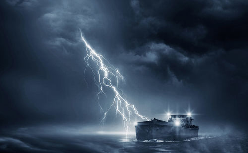 Lightning over sea against dramatic sky