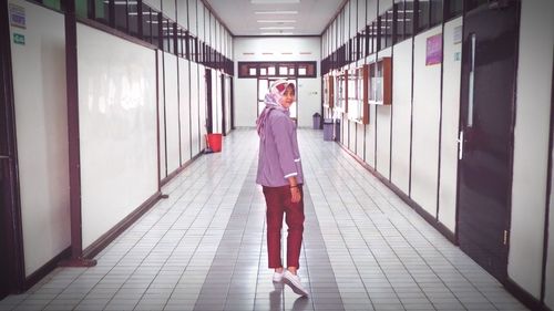 Rear view of woman walking in corridor of building