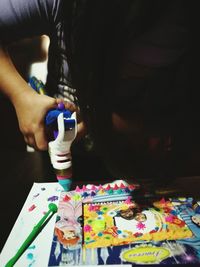 Midsection of woman holding colorful painting on table