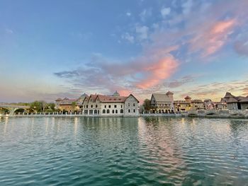 Houses by lake against sky in city
