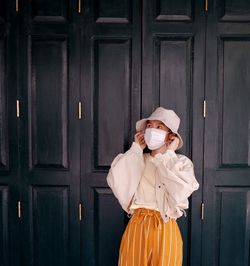 Woman holding umbrella standing against door