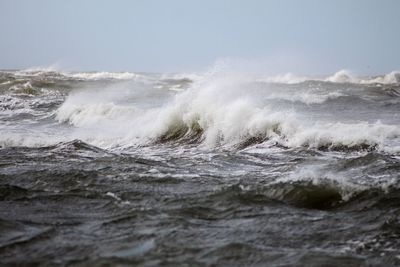 Waves rushing towards shore against sky