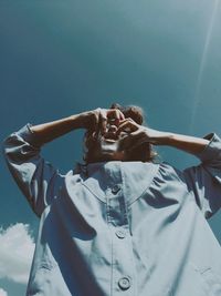 Low angle view of woman wearing mask while standing against sky