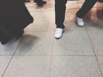 Low section of people standing on tiled floor