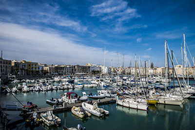 Sailboats moored at harbor against sky