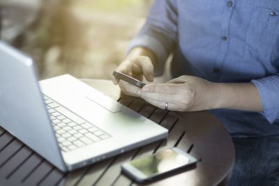 Midsection of man using laptop on table