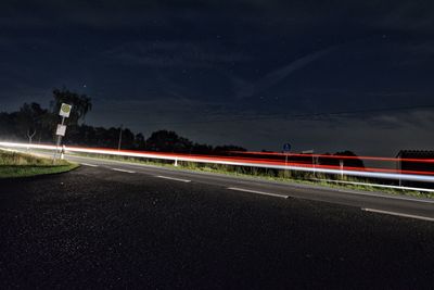 Light trails on road against sky at night