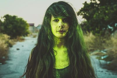 Close-up portrait of young woman standing against tree