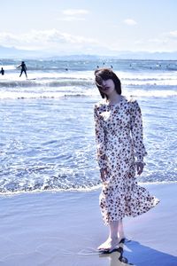 Woman standing on beach against sea