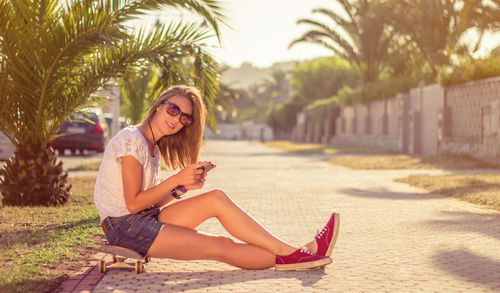 Young woman sitting on mobile phone in park