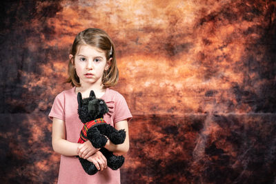Portrait of a girl standing against wall