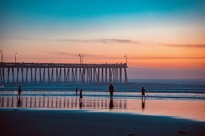 Silhouette pier on beach against sky during sunset