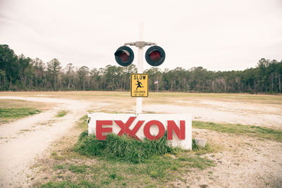 Information sign on road by trees against sky