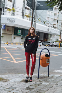 Portrait of young woman standing on road in city