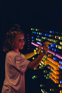 Cute kid boy studying the refraction of light. child playing with colors flasks in dark room 