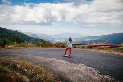 Full length of teenage girl standing on road against sky
