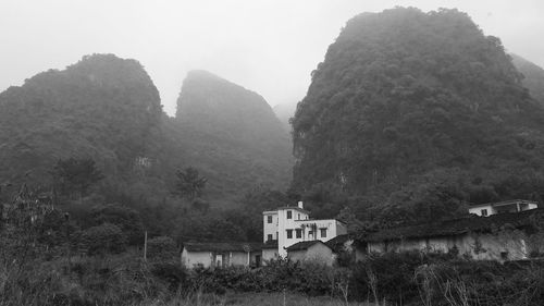 House amidst trees and buildings against sky