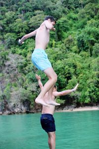 Cheerful shirtless friends jumping in lake
