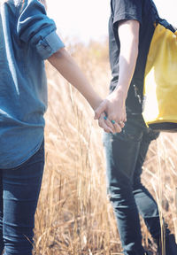 Midsection of couple holding hands standing on land