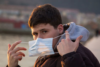 Man putting disposable surgical mask on his face