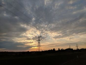 Electricity pylon on field against sky during sunset