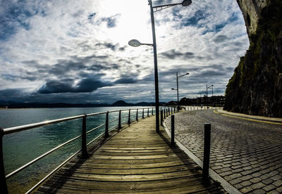 Pier on sea against cloudy sky