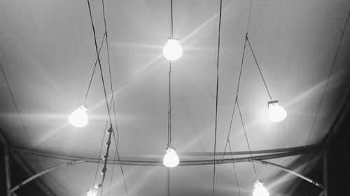 Low angle view of illuminated lighting equipment hanging on ceiling