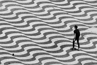 Man walking along square paved with stone forming illusionist pattern