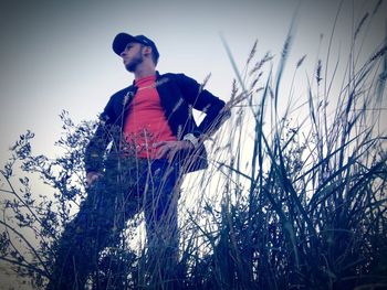 Low angle view of man standing by plants against sky