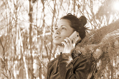 Portrait of young woman standing against plants in winter