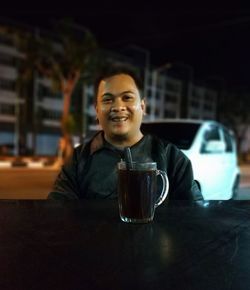 Portrait of smiling young man drinking glass