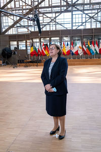 Full length portrait of woman standing against wall