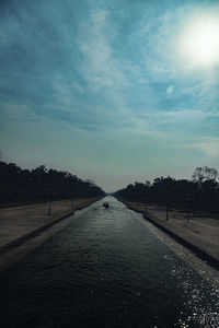 Road by canal against sky
