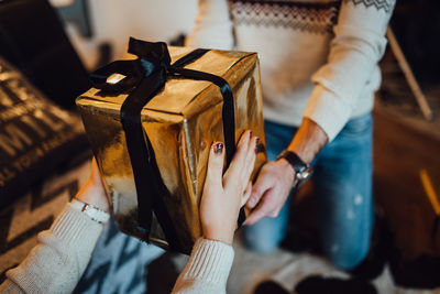 Close-up of woman giving christmas gift to man