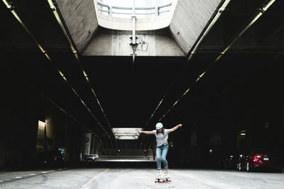 Woman with arms outstretched skateboarding in parking lot