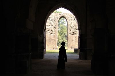 Rear view of silhouette woman standing against building