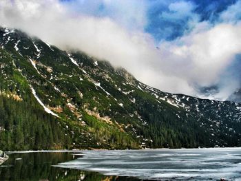 Scenic view of lake by mountains against sky