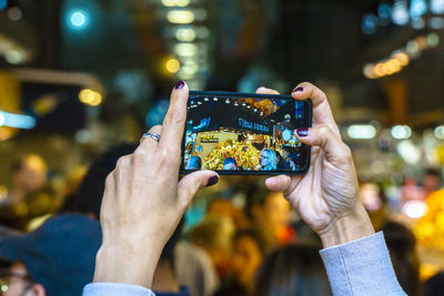 Midsection of woman photographing illuminated mobile phone at night