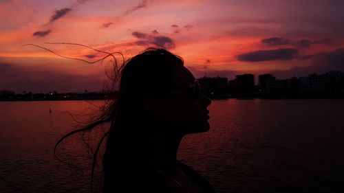 Side view of silhouette woman against lake during sunset