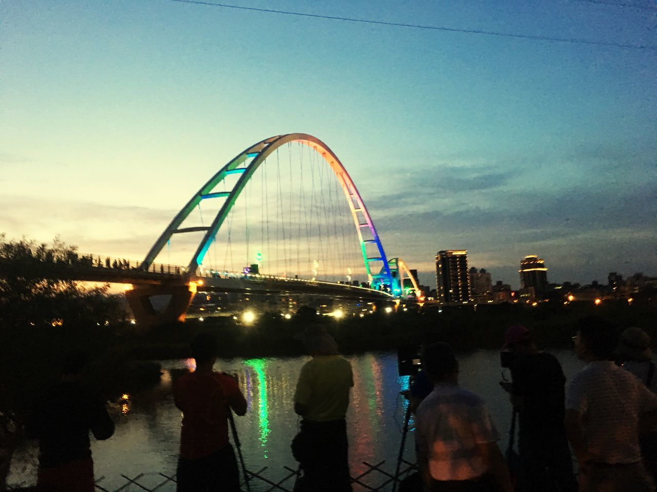 sky, architecture, built structure, large group of people, outdoors, leisure activity, bridge - man made structure, real people, city, men, building exterior, women, day, illuminated, water, nature, cityscape, people