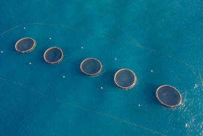 Aerial view of row of fish farms floating in blue water