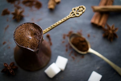 Black turkish coffee with sugar cubes cinnamon sticks and anise star on dark stone slate