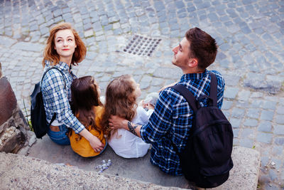 Friends sitting on street in city