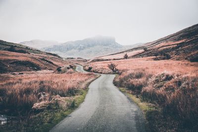 Road leading towards mountains against sky